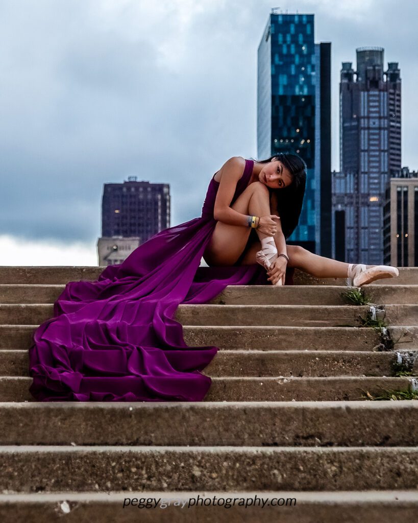 Female dance in pointe shoes sitting on concrete steps in downtown Chicago.