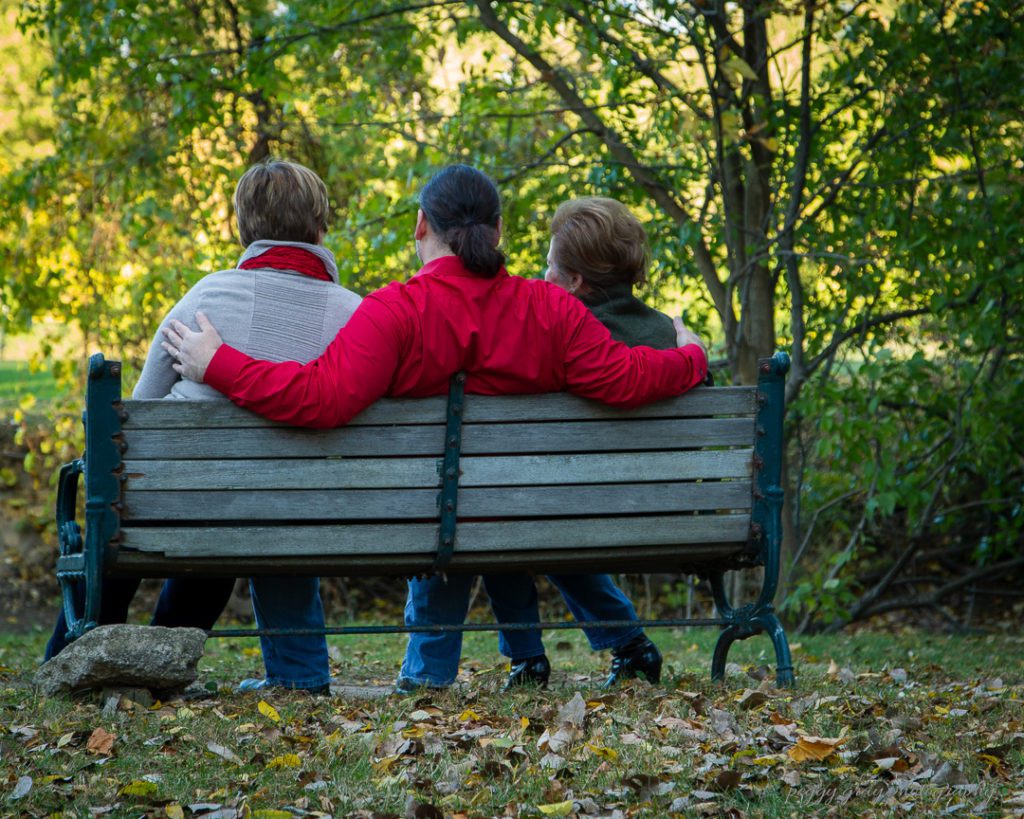 Family photograph of three adults on park bench